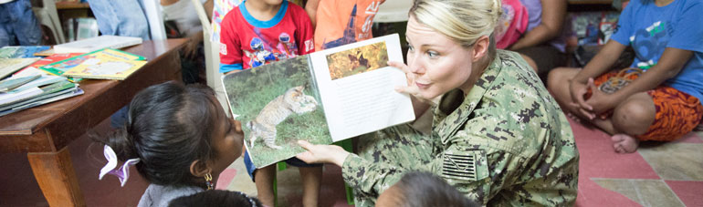 Navy Woman reading book to children