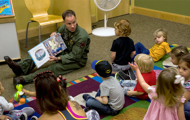 Navy Man reading book to children