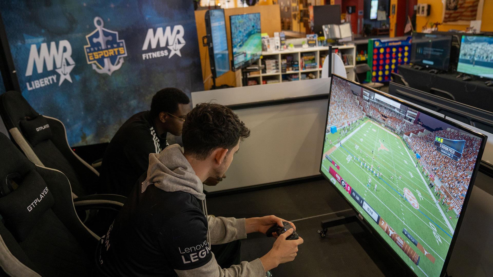 Sailor competes against Madden NFL esports pro athlete Drini in a game of EA Sports College Football at Whidbey Island's Navy MWR Liberty Center.